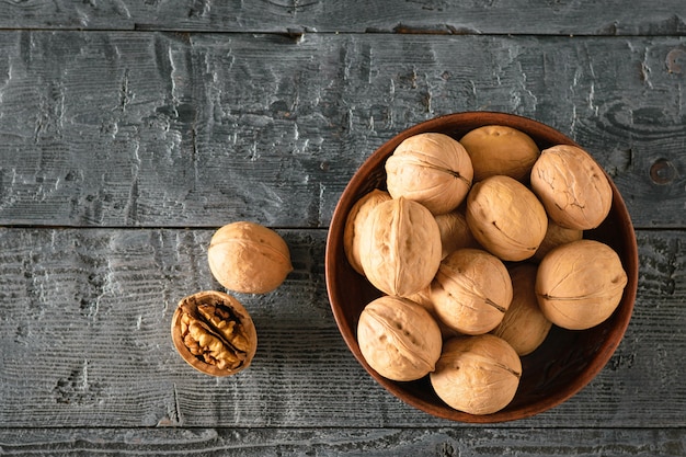 Nueces en un recipiente de arcilla sobre una mesa de madera oscura. Endecha plana.