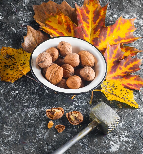 Nueces en un recipiente de esmalte con hojas amarillas caídas