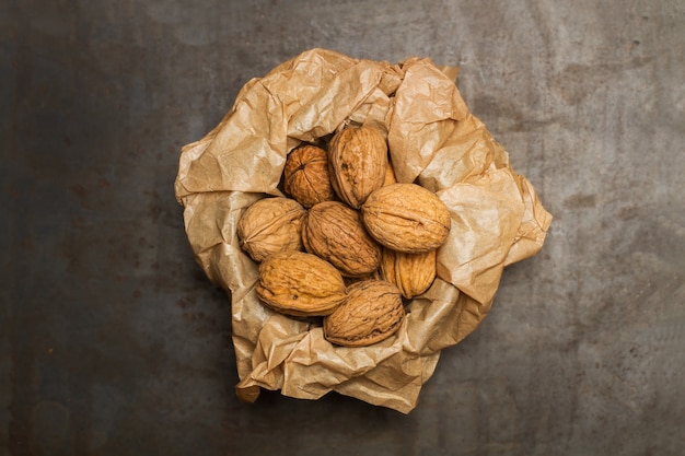 Nueces en un recipiente con un papel arrugado sobre una mesa de metal oxidado