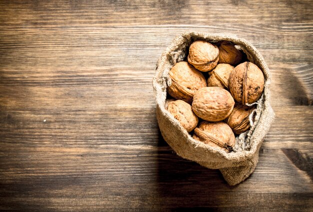 Nueces en saco viejo sobre mesa de madera.