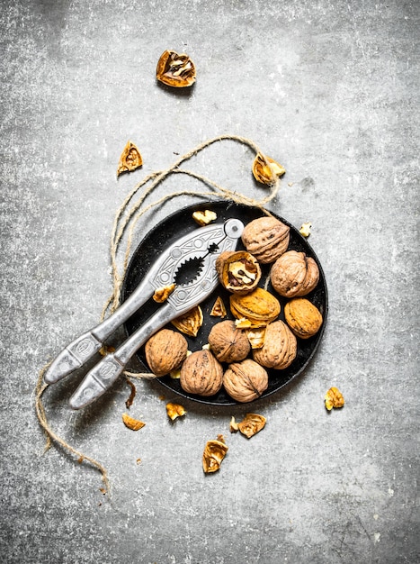 Nueces en un tazón con cascanueces sobre la mesa de piedra