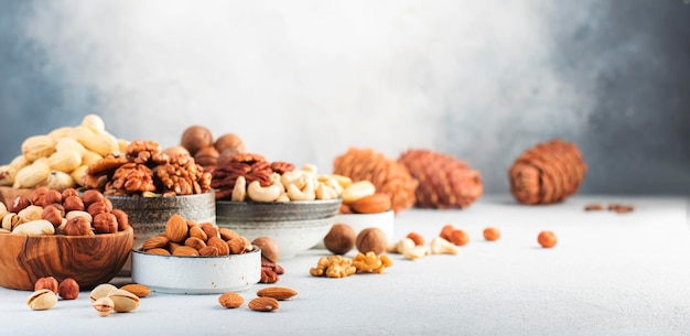 Nueces en tazones Anacardos avellanas nueces pecanas almendras y otros alimentos saludables mezcla de refrigerios en el espacio de copia de fondo de mesa gris