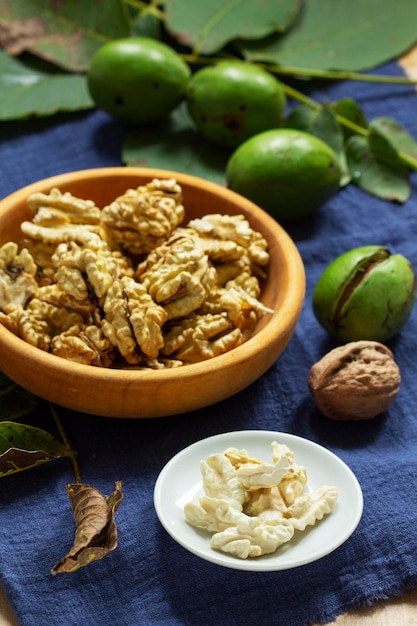 Foto nueces tiernas sin cáscara y hojas de nogal con cáscara estilo rústico