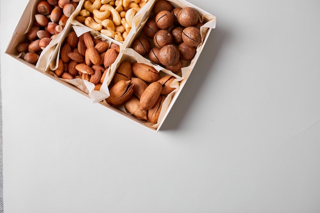 Nueces variadas en una caja de madera nueces pecanas almendras macadamia brasil anacardos avellanas ricas en minerales y proteínas nutrición saludable alta en zinc magnesio y vitaminas concepto de compra de pedidos en línea