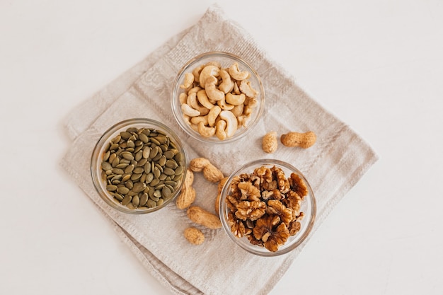 Nueces y vinagre en un paño de cocina de lino sobre una mesa blanca. Nueces, anacardos y semillas de calabaza para una nutrición adecuada. alimentos y nutrientes saludables para el cerebro y el cuerpo