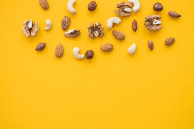 Nüsse mischen für eine gesunde Ernährung Cashew Erdnuss Haselnüsse Walnüsse Mandeln auf gelbem Hintergrund