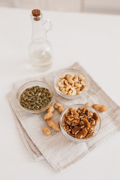 Nüsse und Essig auf einem Leinengeschirrtuch auf einem weißen Tisch. Walnüsse, Cashewkerne und Kürbiskerne für die richtige Ernährung. gesunde Lebensmittel und Nährstoffe für Gehirn und Körper