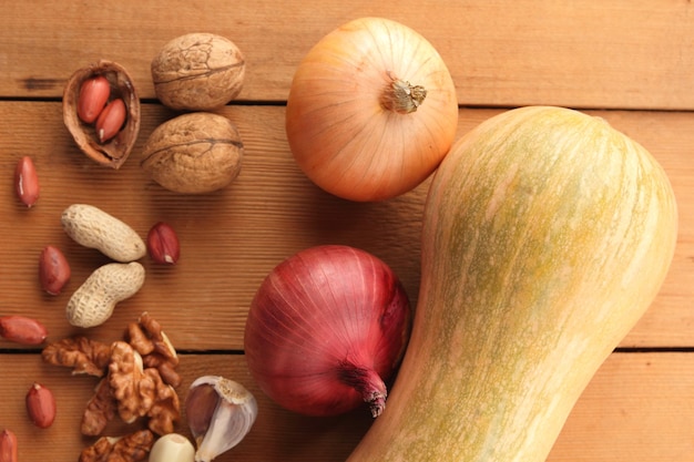 Nüsse, Zwiebel, Knoblauch und Kürbis auf einem hölzernen Hintergrund Nüsse und Gemüse auf einem Holztisch, Nahaufnahme Veganes Lebensmittelkonzept