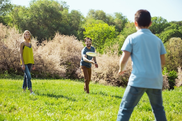 Nuestra actividad. Papá barbudo alegre sonriendo mientras juega un juego con su hijo y su esposa