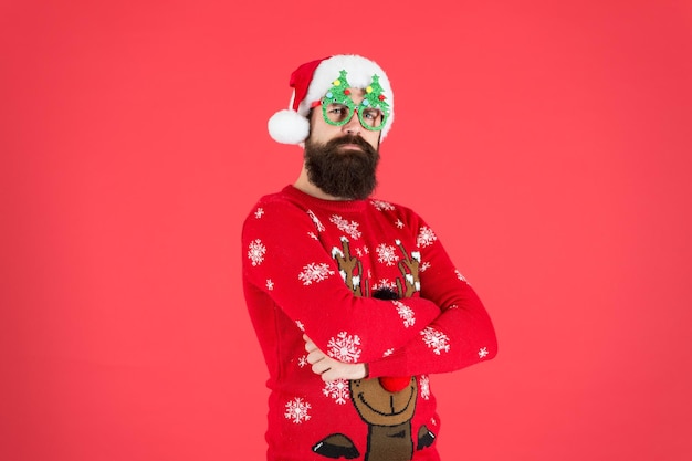 Nuestras campanas tintinean celebración de vacaciones de invierno ho ho ho hombre barbudo sombrero de santa pared roja la navidad está aquí hombre con gafas de fiesta de navidad feliz nuevo año 2020 divertido suéter de punto hipster