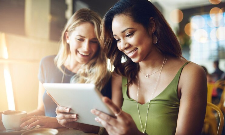 Foto nuestras citas de café son donde tengamos wifi gratis captura recortada de amigas compartiendo algo en una tableta digital mientras están sentadas en un café