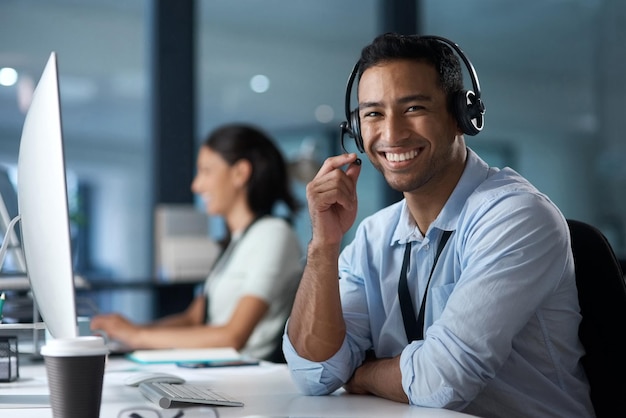 Nuestro índice de satisfacción del cliente lo dice todo Retrato de un joven que usa un auricular y una computadora en una oficina moderna