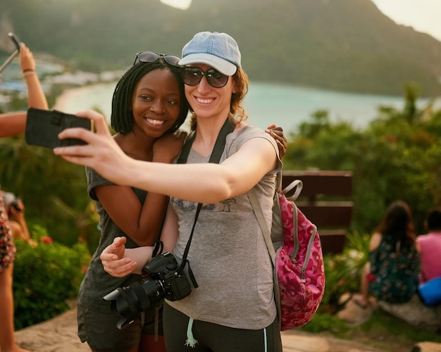 Nuestros amigos van a estar tan celosos Retrato de dos amigos felices tomándose una selfie en unas vacaciones en la isla