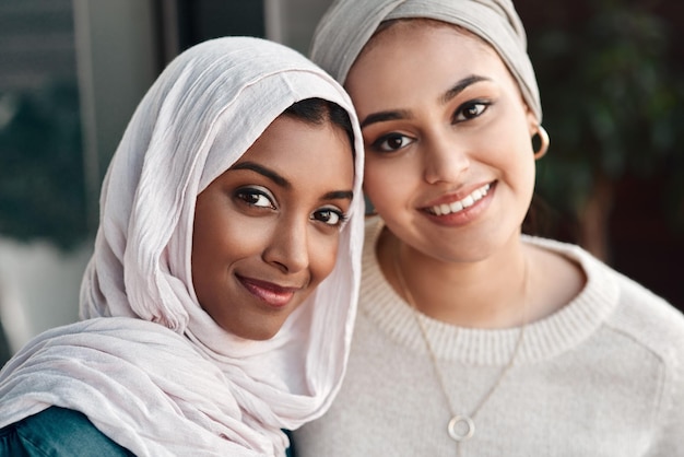 Nuestros fines de semana van muy bien, gracias Retrato recortado de dos amigas jóvenes cariñosas pasando el rato juntas en un café mientras visten hiyab