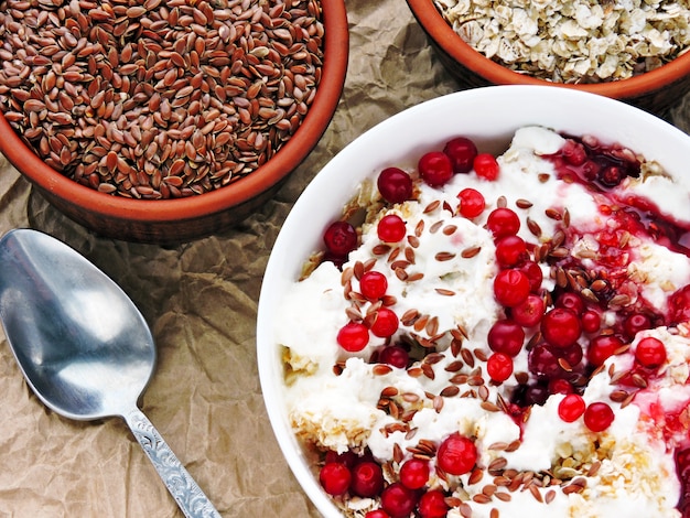 Nützliches Frühstück. Haferflocken mit weißem Joghurt, Marmelade, Leinsamen und Preiselbeeren.