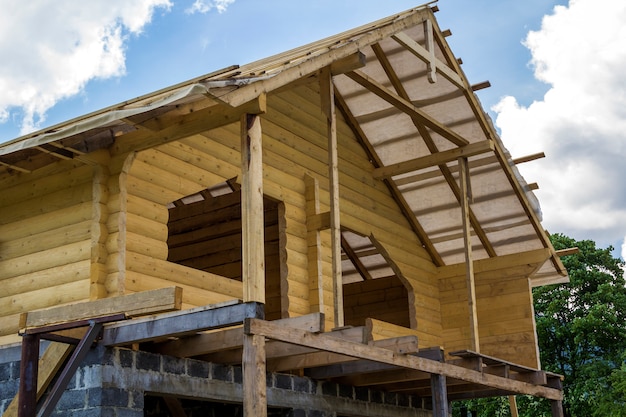 Foto nueva casa de madera natural en construcción. paredes de madera y techo en el alto garaje de piedra de ladrillo. propiedad, inversión, construcción profesional y concepto de reconstrucción.