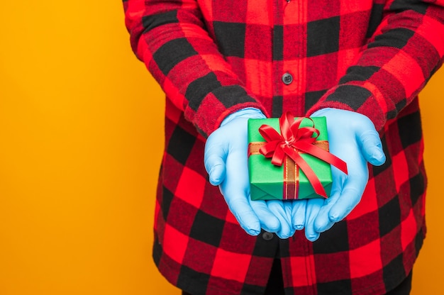 Foto nueva celebración de navidad normal, persona con caja de regalo con guantes