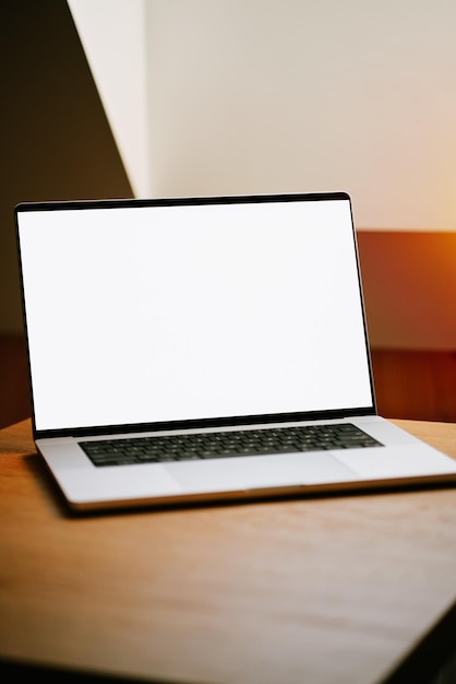 Una nueva computadora portátil profesional está en la mesa de madera Plantilla de diseño para aplicación o sitio web Maqueta de una computadora portátil con una pantalla en blanco en el interior de una casa moderna Computadora portátil de aluminio plateado