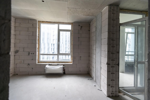 Una nueva habitación de apartamento sin terminar con las paredes de ladrillo desnudo sin decoración.