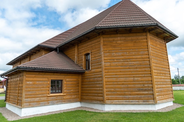 Nueva y moderna casa de troncos de madera Vista de una casa de pueblo contra un cielo azul claro tejas