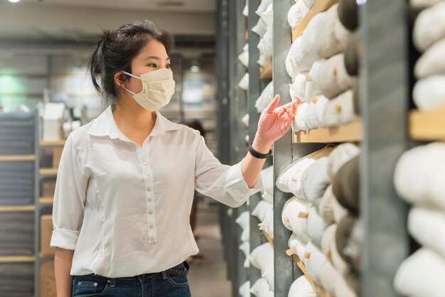 Nueva normalidad después de la epidemia de covid, joven mujer asiática inteligente que compra un nuevo estilo de vida en la tienda con protector facial o máscara de protección, elija productos de consumo, nuevo estilo de vida normal