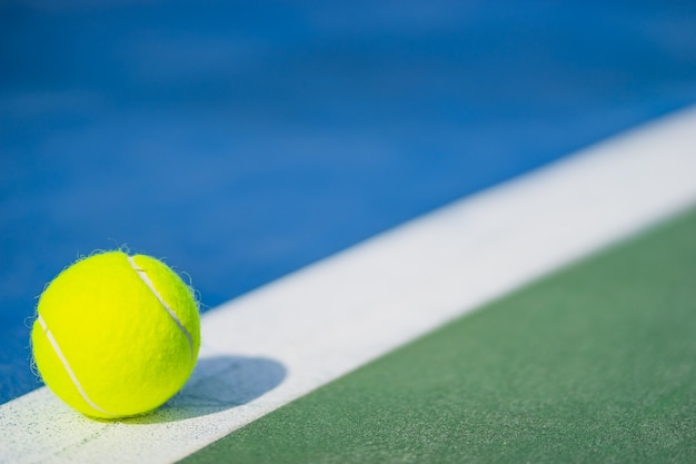 Foto nueva pelota de tenis en línea blanca en el tribunal azul y verde