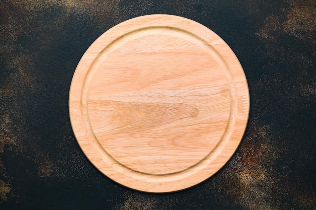 Nueva tabla de cortar de madera redonda para pizza sobre fondo de piedra. Vista superior. Maqueta para proyecto de comida.