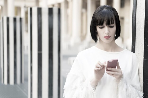 Nueva tecnología para la vida moderna. Mujer con labios rojos en smartphone en parís, francia. Mujer con cabello morena mantenga teléfono móvil. Chica de belleza con mirada sexy. Modelo de moda con dispositivo móvil.