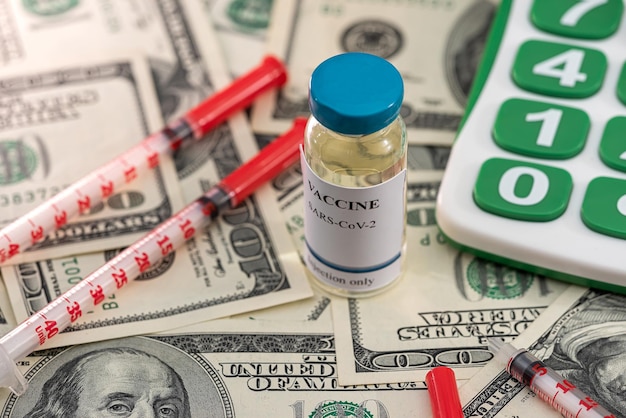 La nueva vacuna de alta calidad que trajeron está junto a una calculadora y billetes de dólar El concepto de cálculo de la vacuna