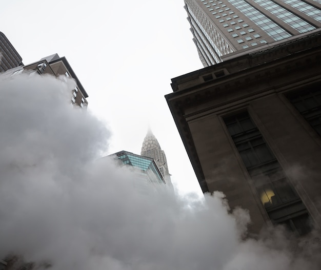 Foto nueva york, estados unidos - 03 de mayo de 2016: empire state building. escena de una calle de manhattan. nube de vapor del metro en las calles de manhattan en nueva york. vista típica de manhattan