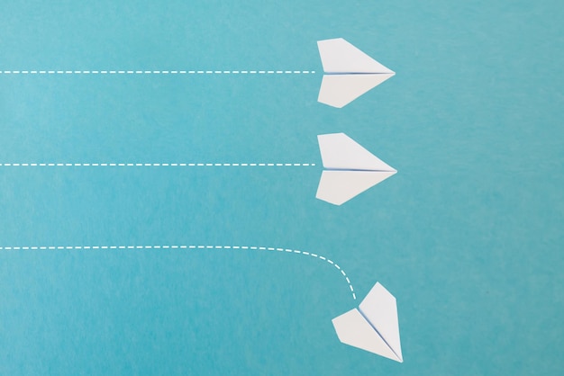 Nuevas ideas creatividad y diferentes soluciones innovadoras concepto de negocio Un grupo de aviones de papel un avión está volando en la otra dirección de manera diferente