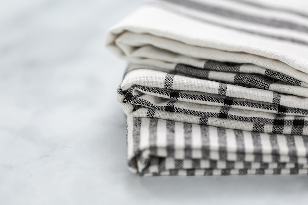 Nuevas toallas de cocina con un patrón negro simple doblado sobre un mostrador de mármol.
