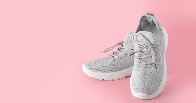 Nuevas zapatillas cómodas, zapatillas deportivas grises con cordones sobre un fondo de color rosa con espacio de copia. Zapatos elegantes y hermosos para mujeres y adolescentes. minimalismo nadie