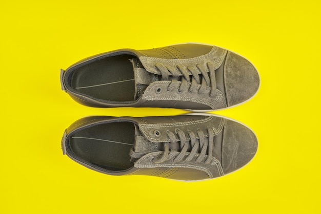 Nuevas zapatillas de cuero gris para hombre sobre fondo amarillo, vista superior. Moda, zapatos de hombre, compras y ventas online, descuentos de temporada