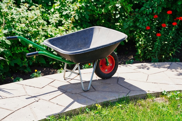 Nuevo carrito de jardín de plástico y metal en un jardín botánico funciona en la parte del jardín de flores ...