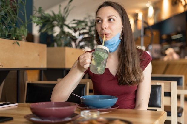 Nuevo concepto normal de mujer con máscara comiendo en restaurante