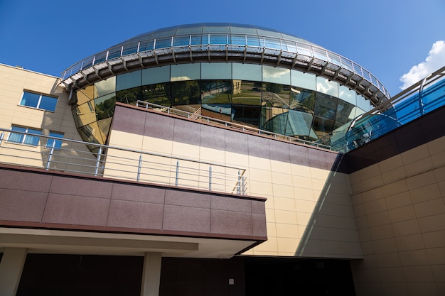 Nuevo edificio de colores claros con la parte superior esférica revestida con paneles de vidrio dorado contra el cielo despejado