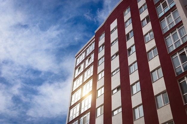 Nuevo edificio de varios pisos contra el cielo en cuyas ventanas se refleja el sol