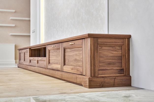 Nuevo y elegante mueble de TV hecho de chapa y madera maciza de nogal con asas doradas vista de ángulo bajo