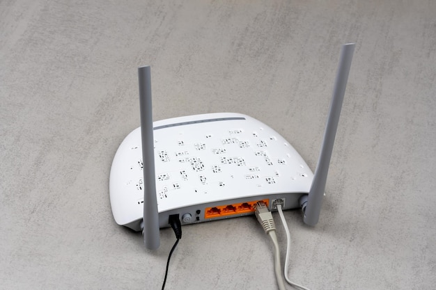 nuevo enrutador Wi-Fi blanco con antenas grises en una vista trasera de fondo gris