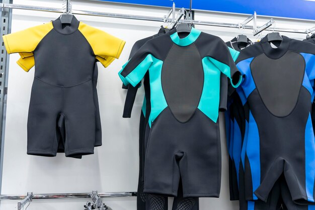 Foto nuevos trajes de neopreno para adultos y niños en una percha en una tienda de artículos deportivos