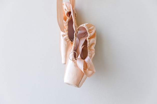 Nuevos zapatos de ballet beige pastel con cinta de raso aislado sobre fondo blanco. Zapatillas de punta clásica bailarina para entrenamiento de danza. Concepto de escuela de ballet, espacio de copia