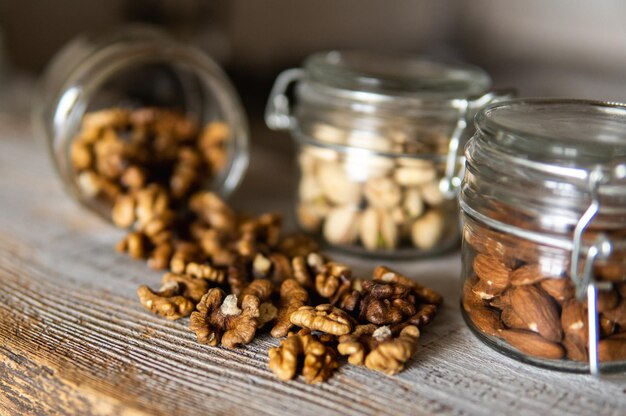 Nuez esparcida en la mesa blanca vintage de un frasco saludable proteína vegetariana comida nutritiva