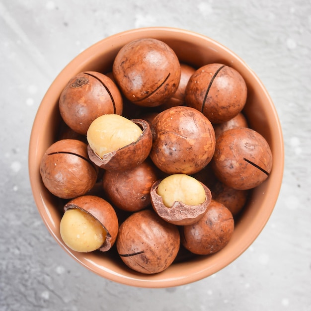 Foto nuez de macadamia. nueces de macadamia en una cáscara, en un bol. sobre un fondo de piedra. las nueces de macadamia son ricas en varios oligoelementos y vitaminas.