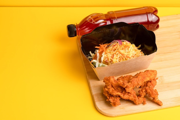 Nuggets com salada e suco de frutas vista lateral de fundo amarelo