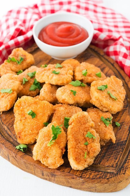 Nuggets de frango caseiro com ketchup em uma placa de madeira