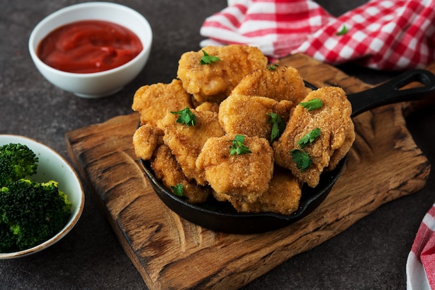 Nuggets de frango caseiro com vegetais em uma placa de madeira, foco seletivo