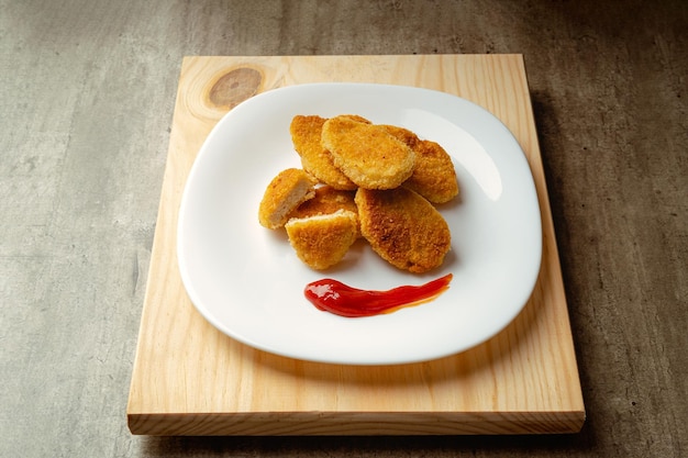 Nuggets de frango com fundo de madeira de pão frito crocante deliciosos nuggets de frango com molho de tomate pronto para comer