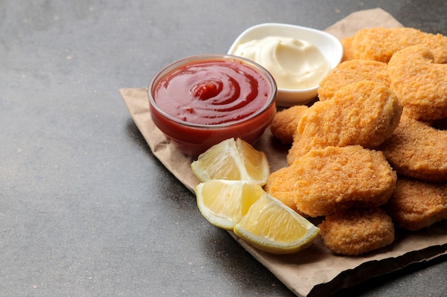 Foto nuggets de frango com molho branco e vermelho em um fundo marrom. comida rápida