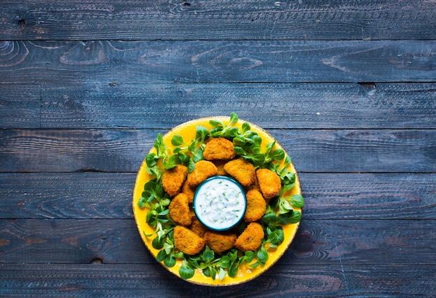 Nuggets de frango com molho de iogurte na madeira